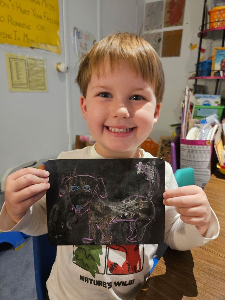 A boy proudly holding up his artwork